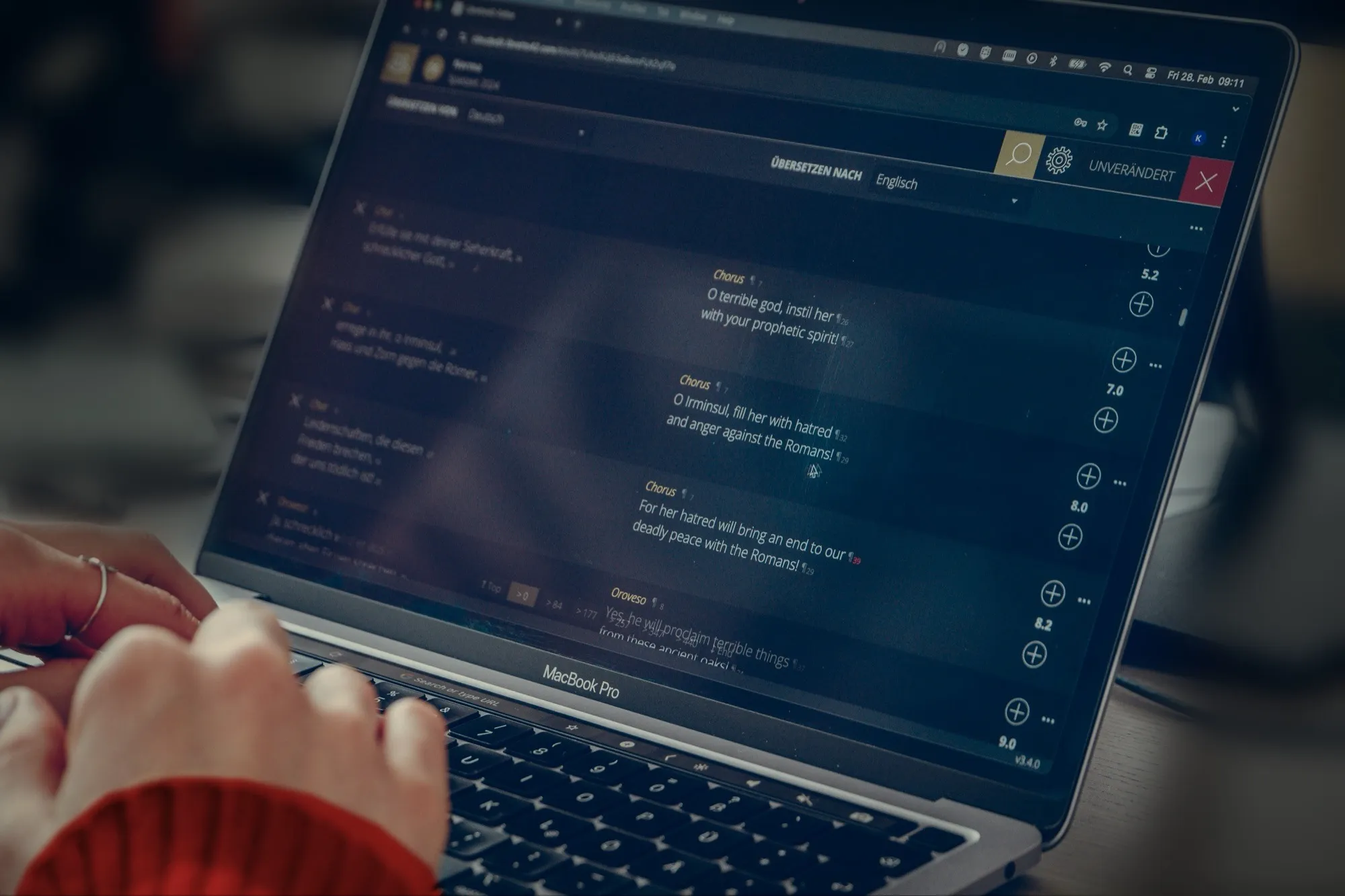 Hände auf der Tastatur eines Laptops, auf dem Bildschirm der Cloud-Editor mit einer Übersetzung vom Deutschen ins Englische