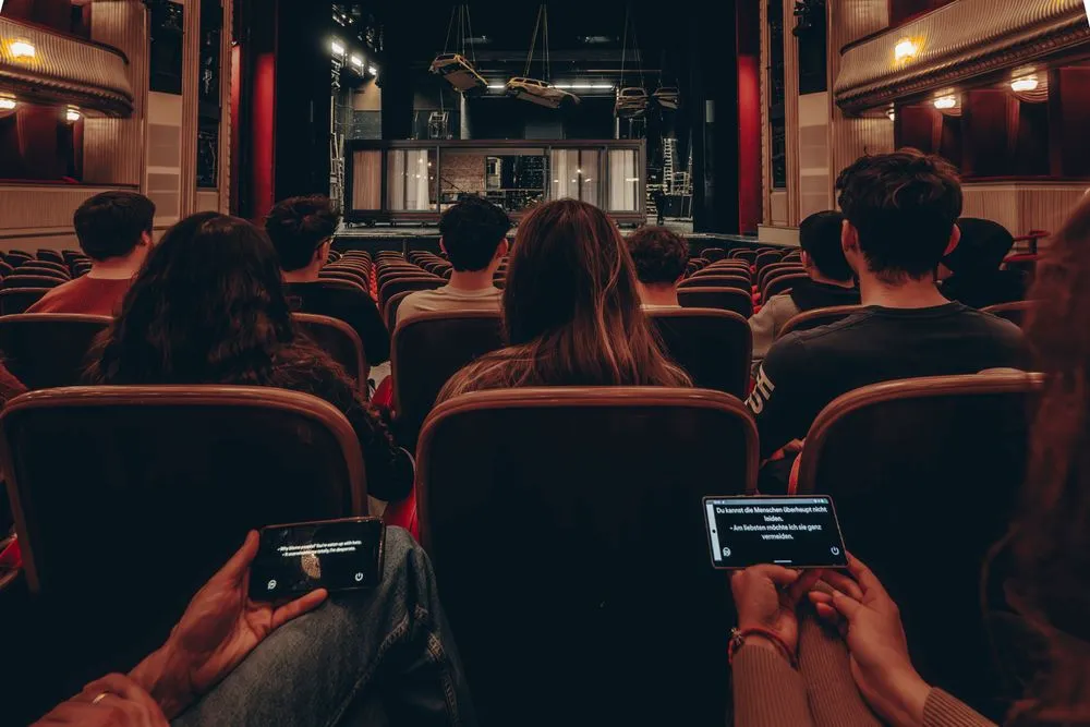 Gäste im Burgtheater verfolgen die Untertitel live auf dem eigenen Smartphone